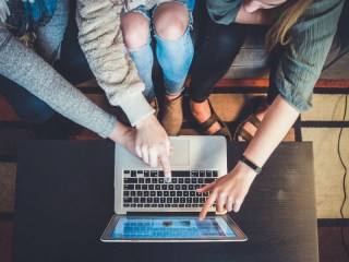 Stock image of a group gathered around a laptop