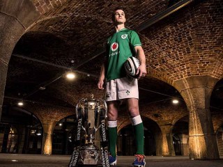 Jonathan Sexton holding a rugby ball beside the Guinness Six Nations cup 